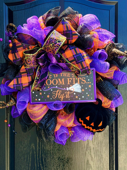 Halloween wreath with purple, orange, and black ribbons on a door.